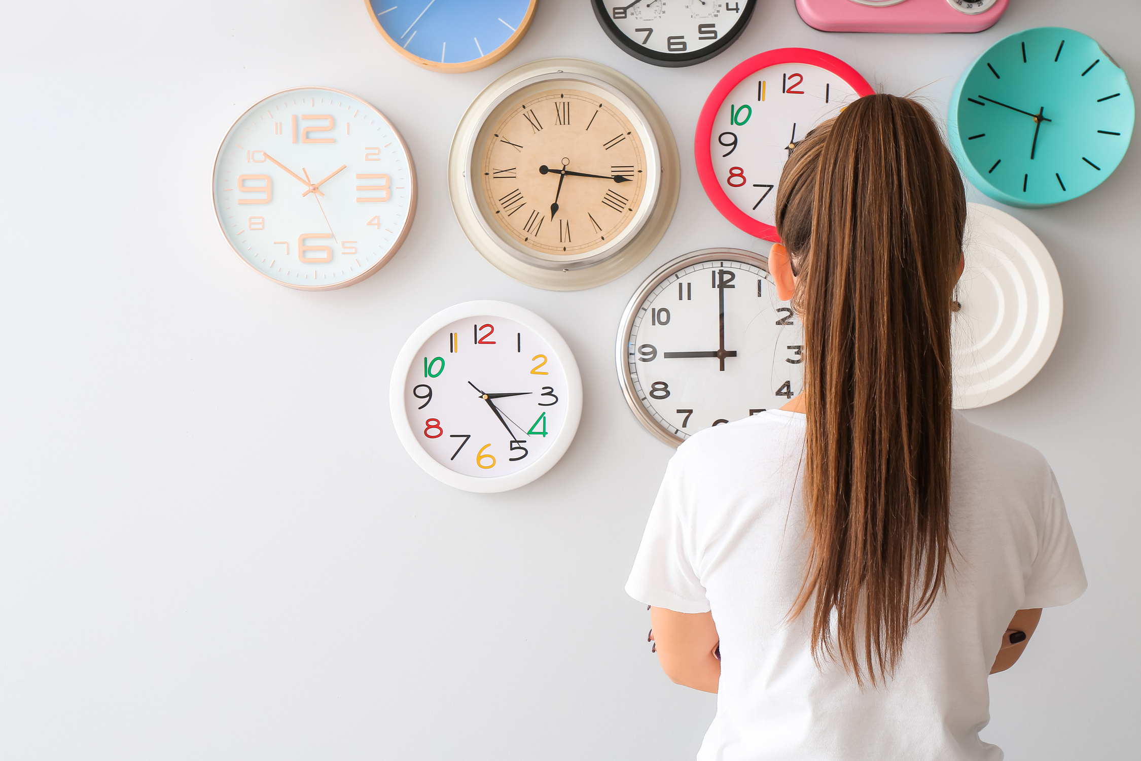 Young Woman Looking at Different Clocks